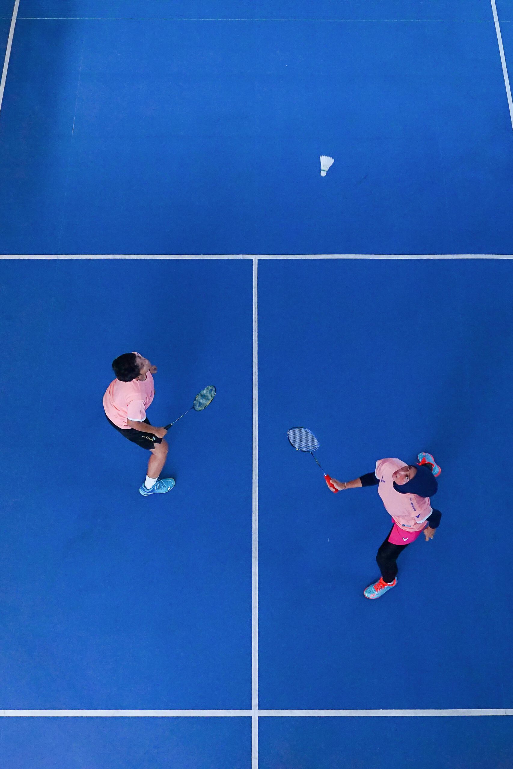 Un jeune homme et une jeune femme jouant au badminton sur un terrain bleu
