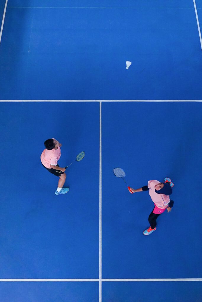 Un jeune homme et une jeune femme jouant au badminton sur un terrain bleu